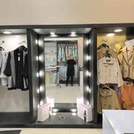 آینه فروشگاه نور پردازی شده با رگال لباس دو طرف